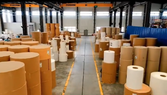Warehouse aisle lined with rolls of kraft and white paper